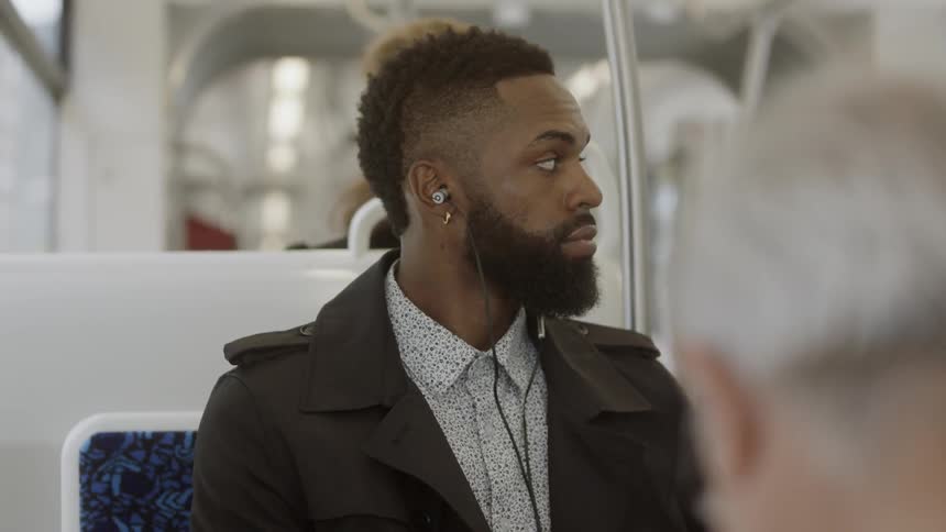 Man listens to music through earbuds while sitting on the bus