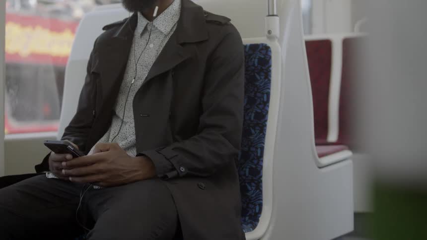Man sits on train and playing with cell phone