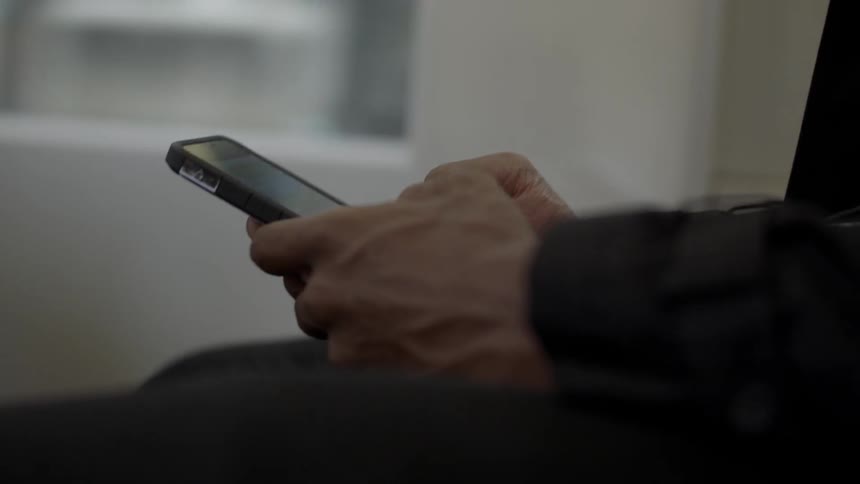 Person sits in vehicle and typing on cell phone