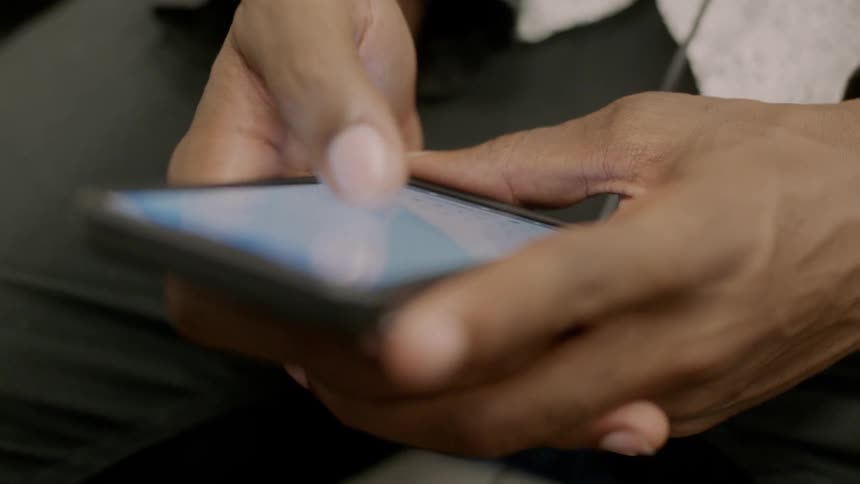 A person scrolls on their phone with their thumb