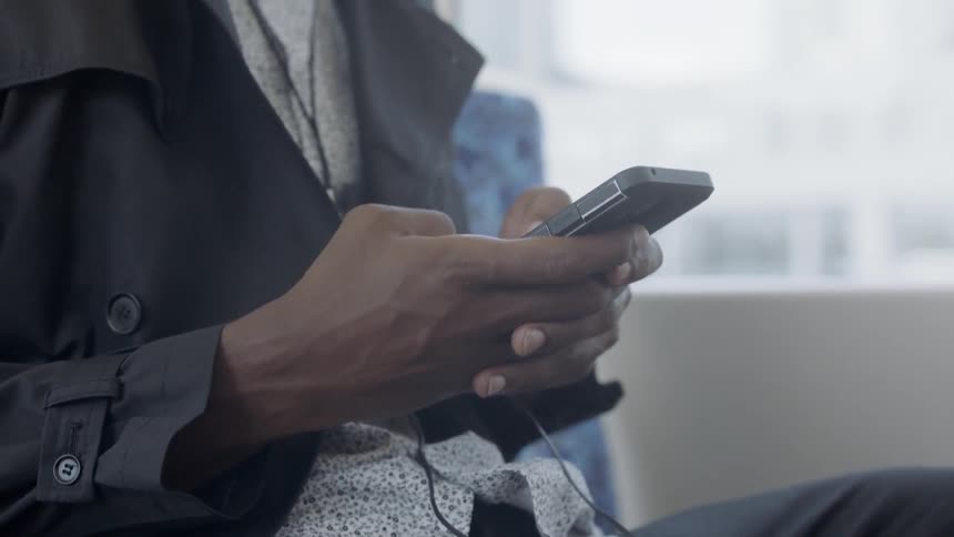 A seated man tapping on a phone in his hands