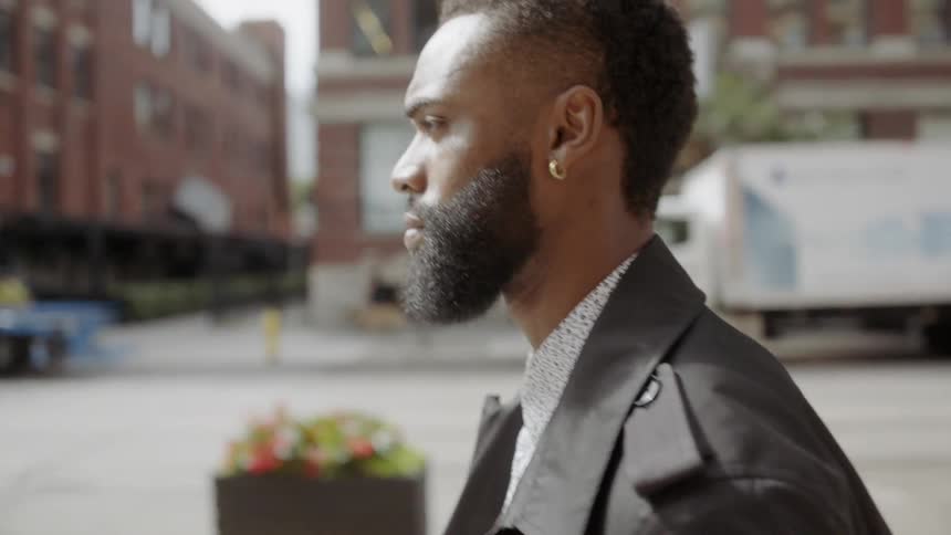 A young black man walks along a city street