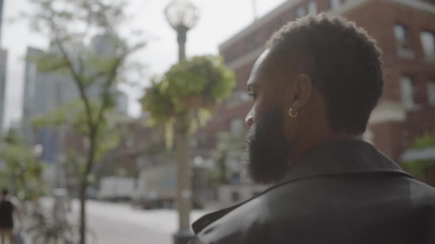 A black man walking down the sidewalk in a city