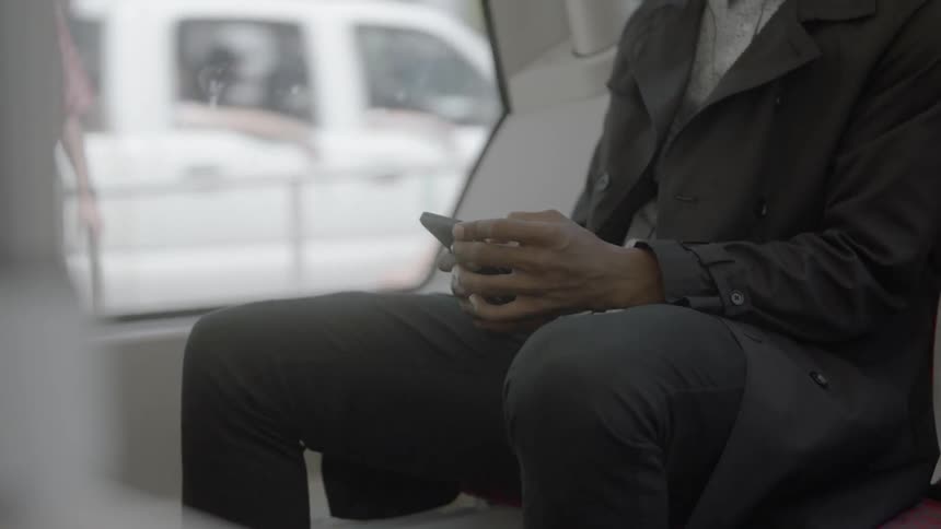 A man sitting on a bus using his phone