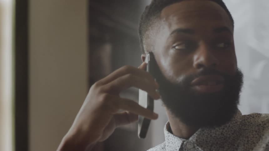 Man sitting indoors talks on phone