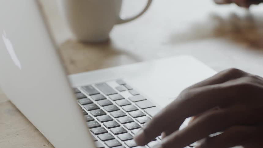 A man stops typing on his laptop to answer his phone