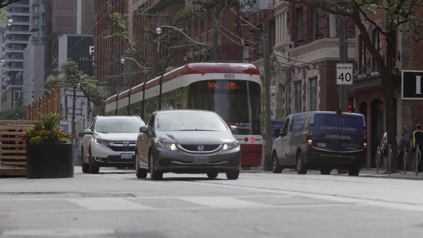 City traffic moves along the road during the middle of the day