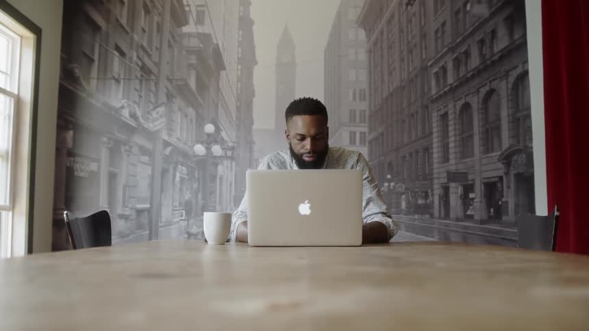 Man types on apple computer sitting on conference table