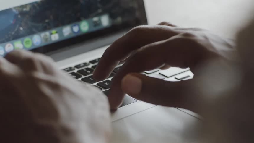 A black person typing on a laptop during the day