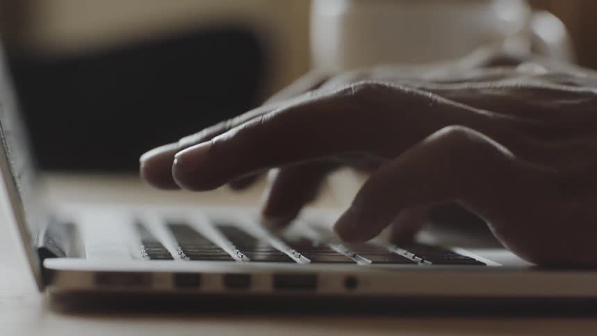 Two hands typing on a slim laptop keyboard