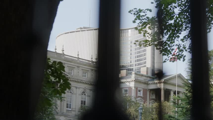 Looking through a gate at a tall office building behind two large homes