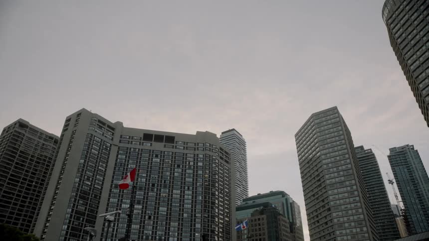 Flags blowing in the wind in front of tall city buildings
