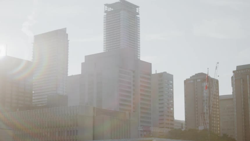 Sunlight shines behind skyscrapers in a city