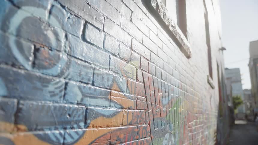 People stand in an alley where colorful graffiti is painted on the building walls