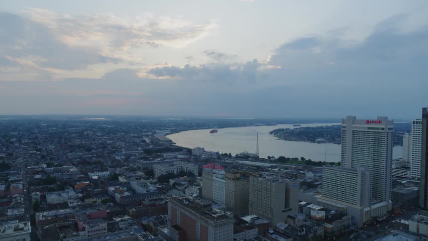 On an overcast and cloudy day and sprawling city can we seen next to a wide river