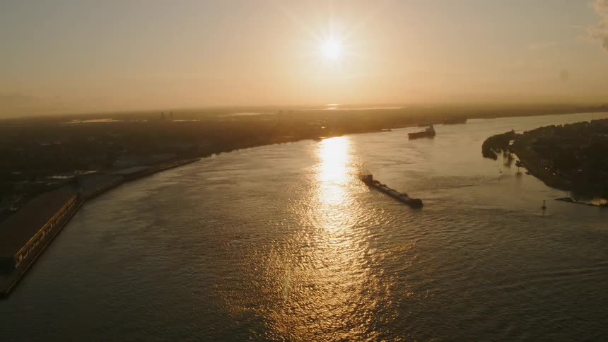 Long barges in a harbor with buoys just off shore at sunset