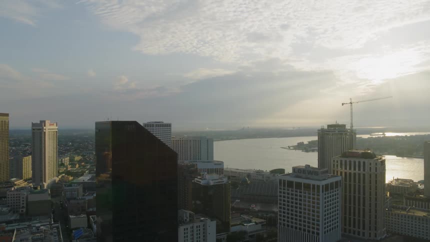 Buildings in a city sit next to a river under a cloudy sky