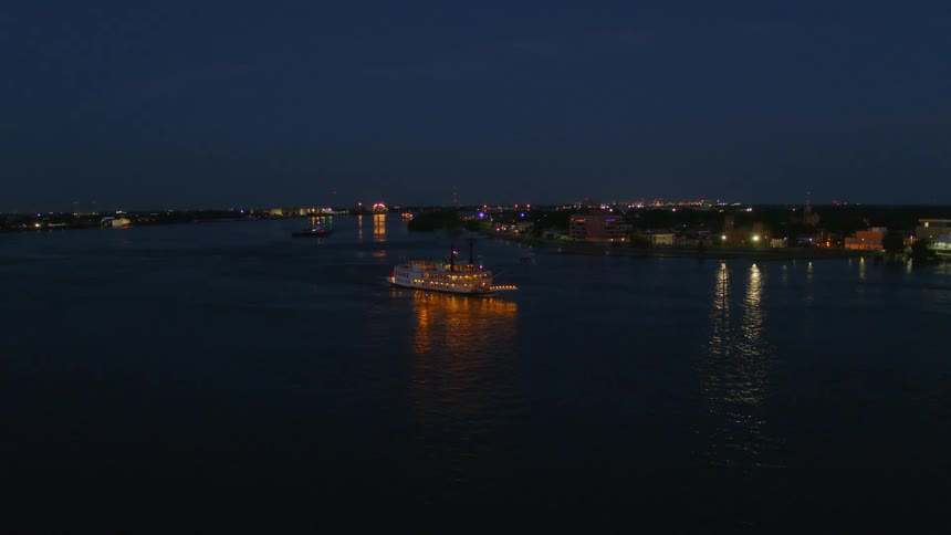 A cruise ship traveling along a river through a city at night