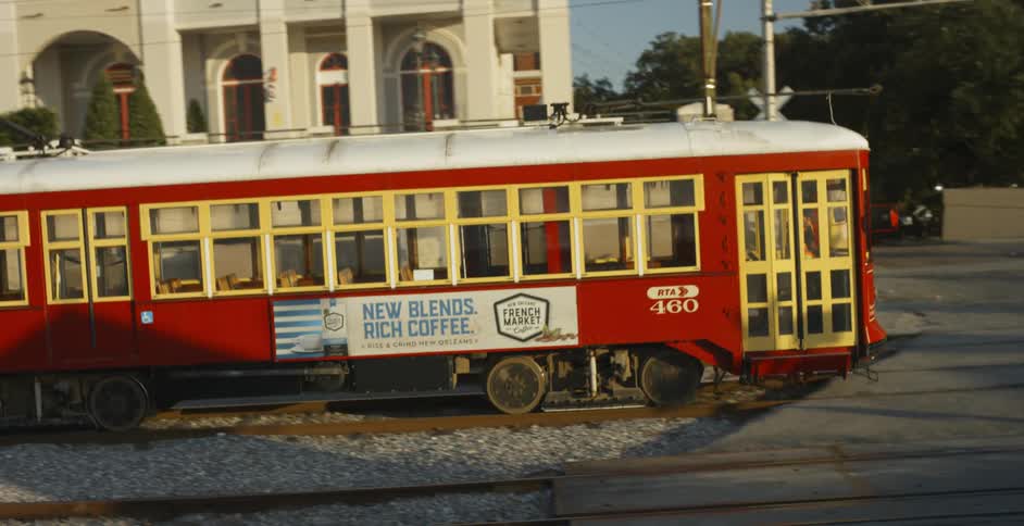 Empty tram passes by a building in the city at sunset