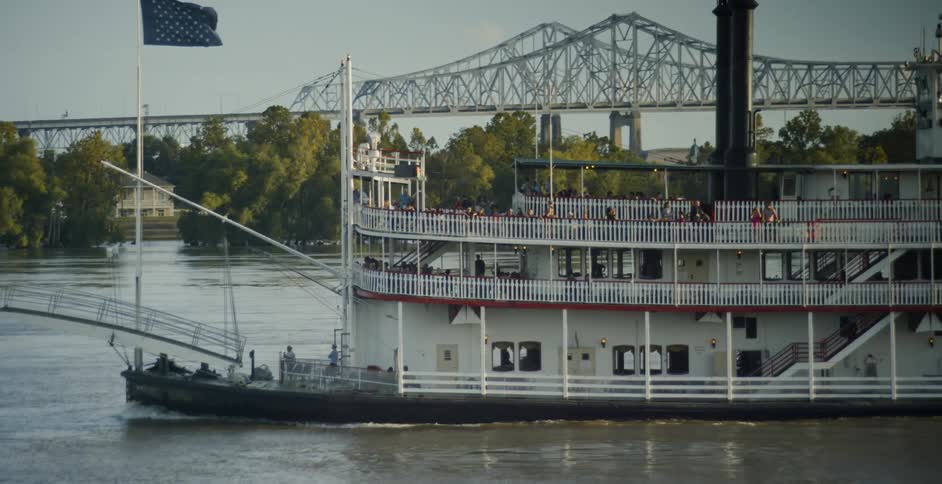 Riverboat sailing on a river in front of a bridge