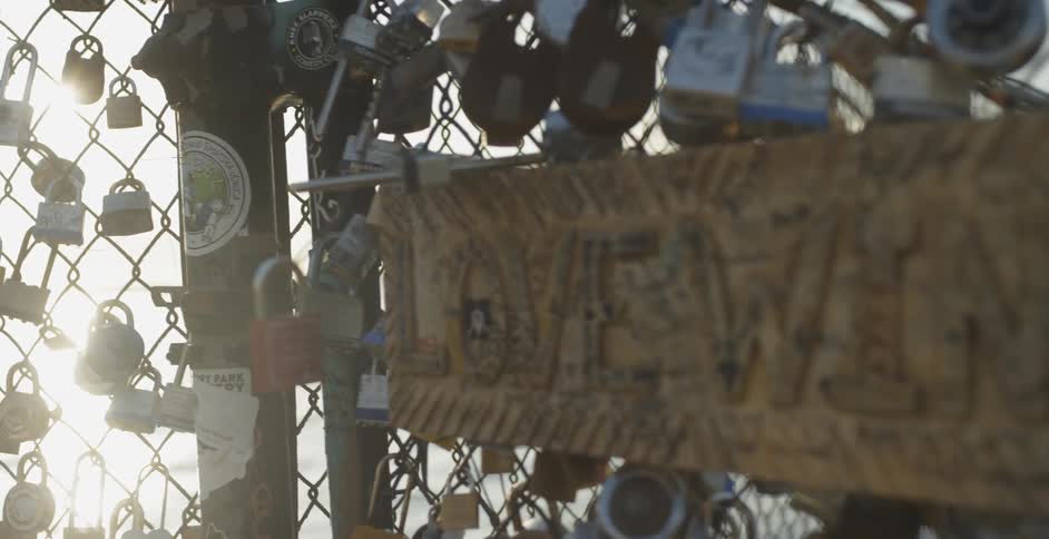 A chain link fence covered in signed locks with a sign that says love wins