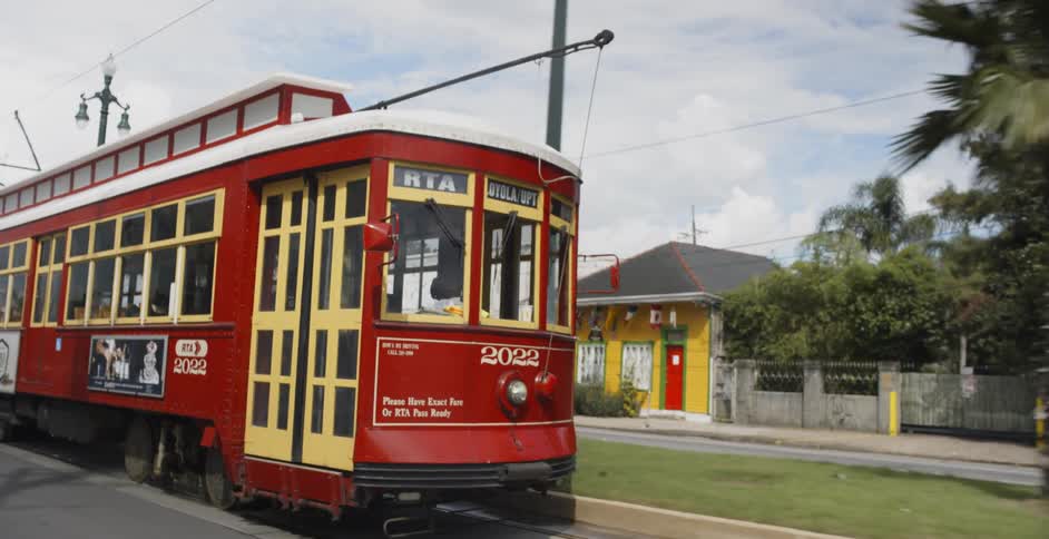 Trolley car travels down the tracks as cars and trucks go in the opposite direction