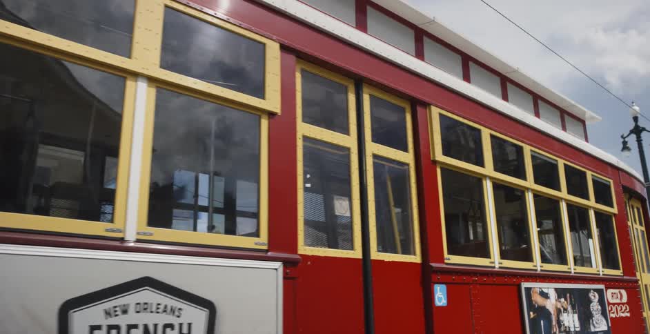 A tram with advertisements for coffee and alcohol makes its way through city streets