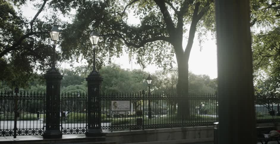 A person sits on a park bench while another one sleeps