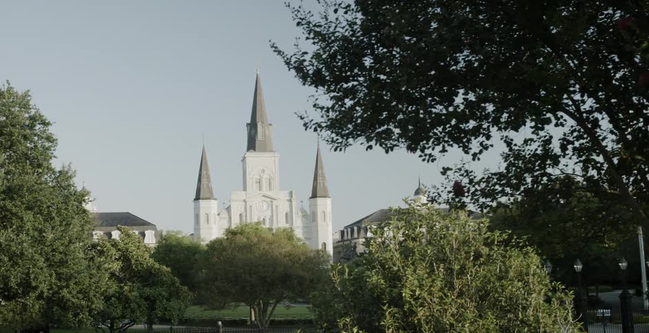 A cathedral with three tall spires viewed from a tree lined park