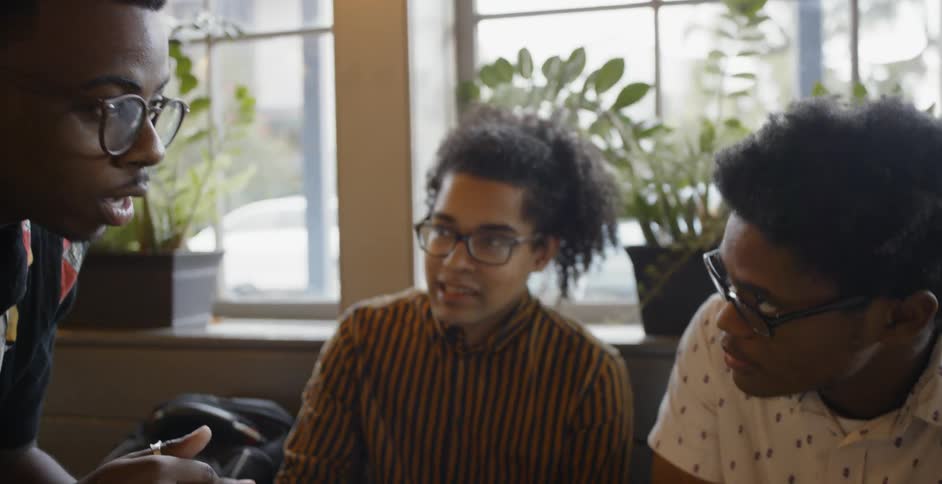 Two men and a woman sitting around a table discussing something together