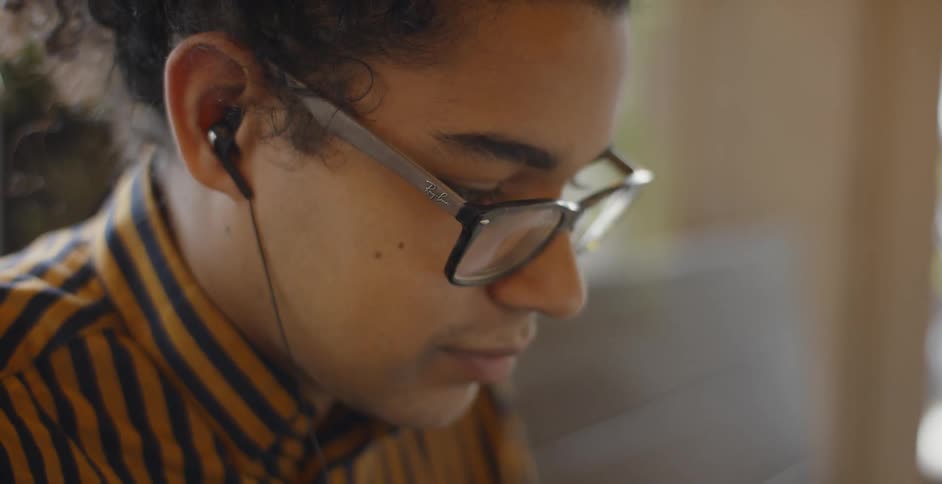 A girl wearing glasses listens to something on her headphones
