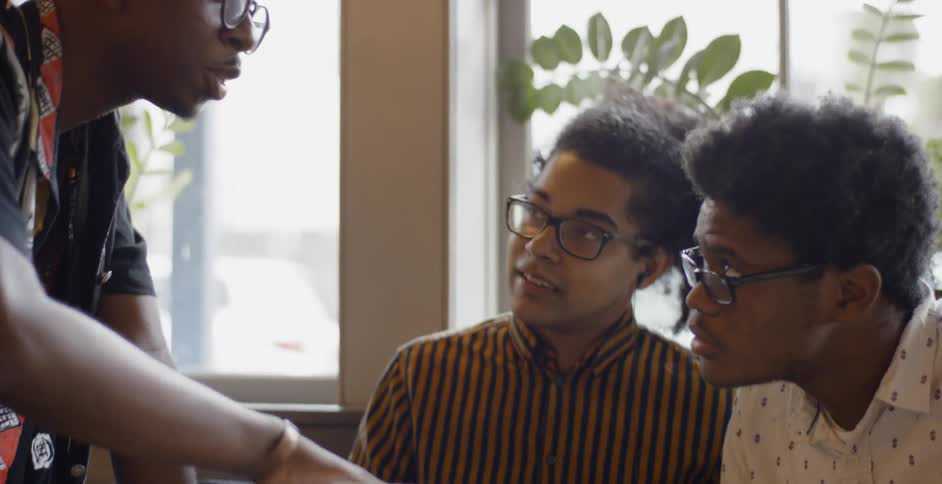 Three friends look at laptop in cafe