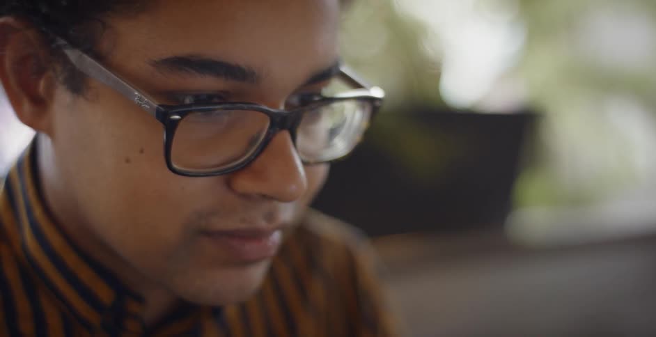 A man with glasses looks at something with a slight smirk