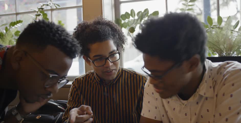 Three people study laptop screen talking and laughing