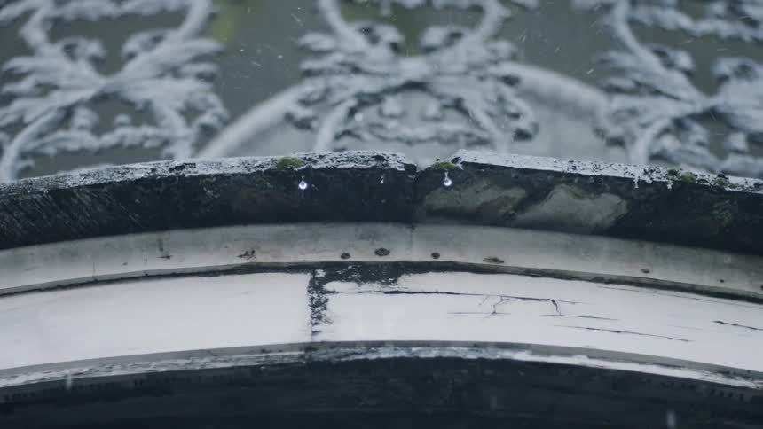 Rain falls and splashes on an outdoor surface