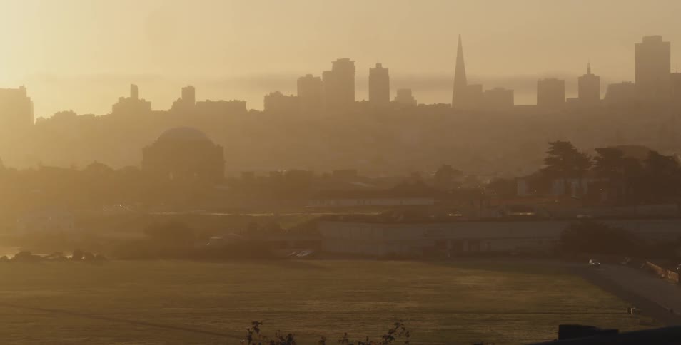 A hazy city skyline near a park and river