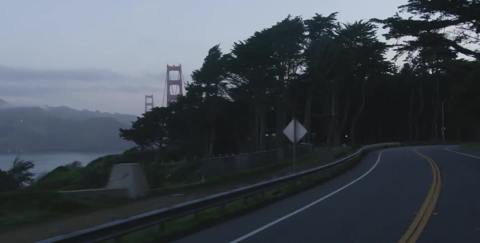 Car coming from the golden gate bridge turns on its lights and drive at dusk