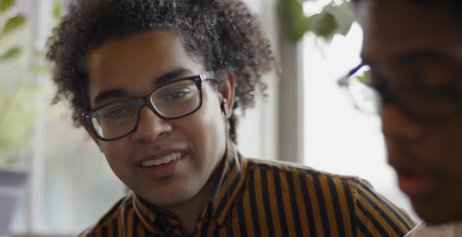 Two young man talking in front of a window with potted plants