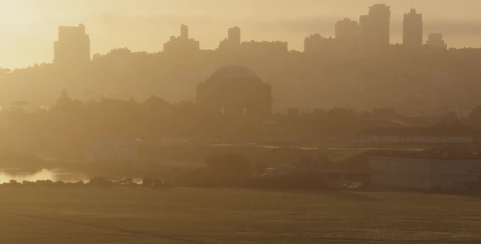 The silhouette of a dome and city buildings along a river in the haze