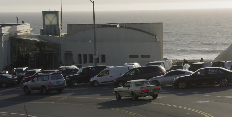 Car drives past parked cars near beach