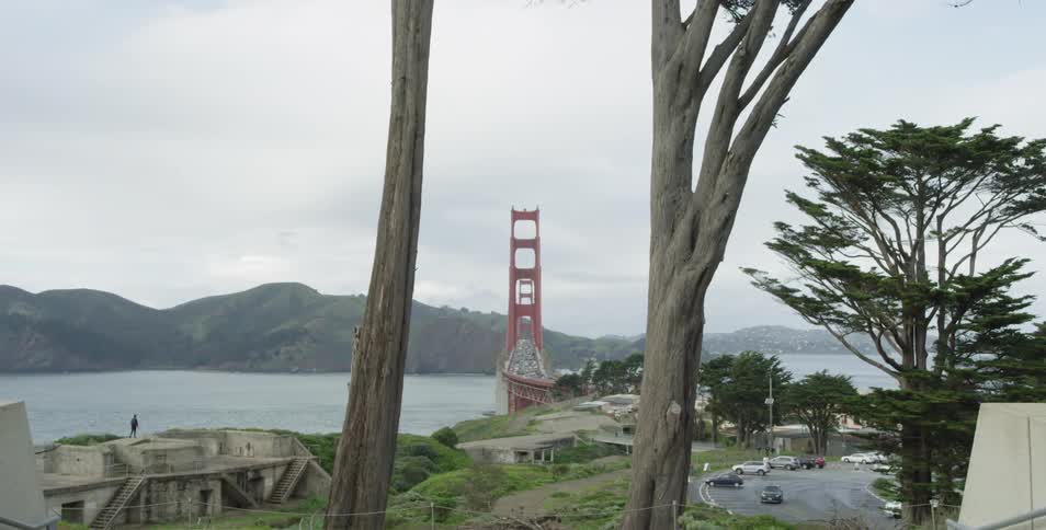A suspension bridge over a body of water near a parking lot