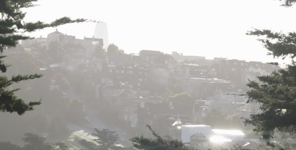 The sun shines down on homes built on a slope and reflects off the snow