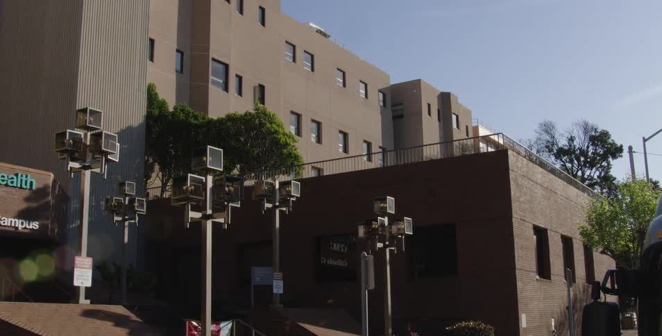 A large medical center with a brown facade has a number of outdoor lamps shaped like cubes