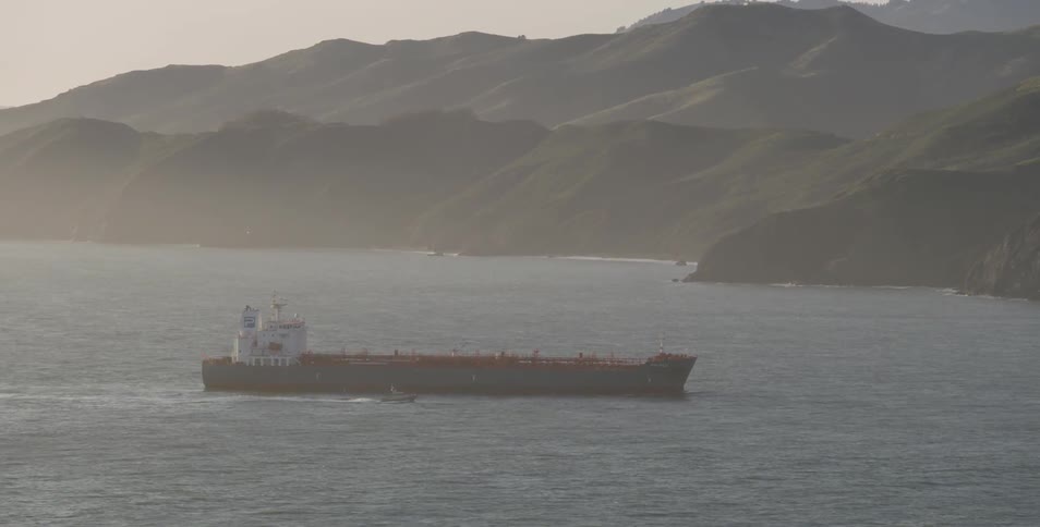 A barge traveling on a body of water near an island