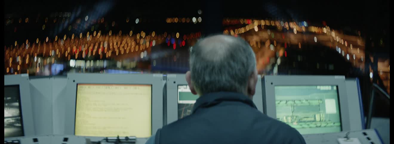 Man sits in front of the computers at the air traffic control tower by night