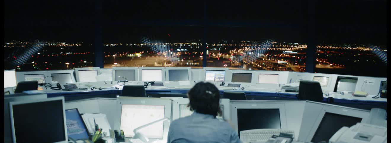 A person hanging up a phone in a command center at night