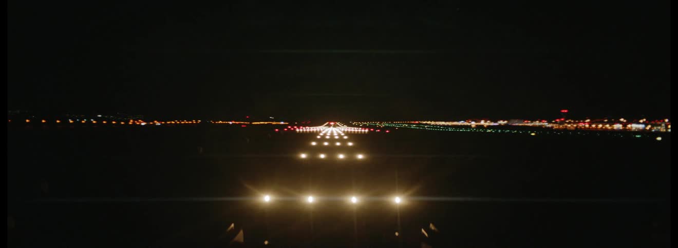 On a very dark night a brightly illuminated airport runway lies ahead