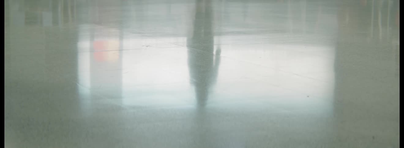 A highly polished floor reflects the silhouette of a person walking