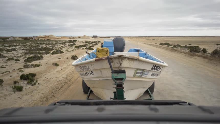 A truck tows a boat across the desert