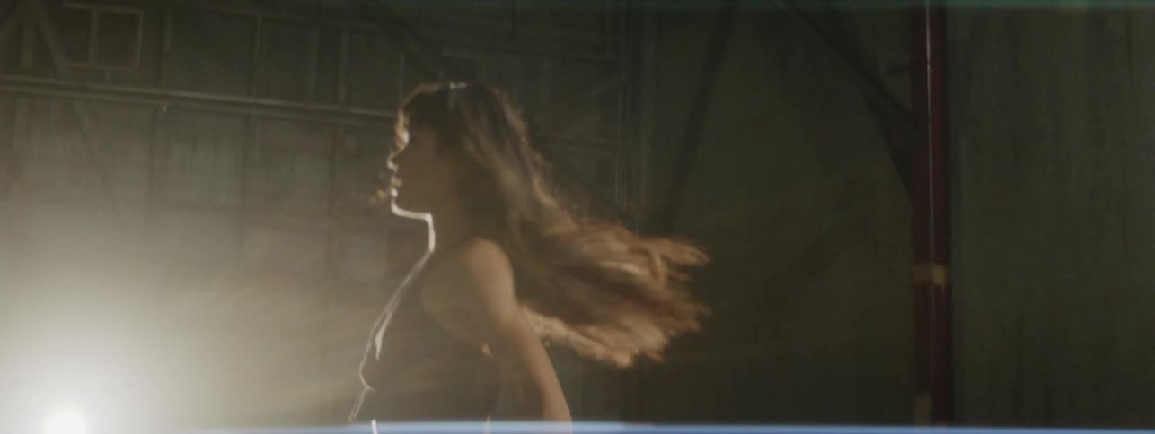 A woman dances and twirls with a bright spotlight behind her